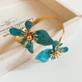 Eleganter goldfarbener Armreif mit zwei exquisiten blauen Emaille-Blumenmotiven. - Gold-Blau