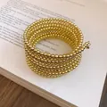 Close-up detail of a minimalist gold multi-layer beaded wrap bracelet with vintage style - Round / Gold