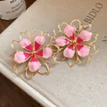 Close-up detail of vintage pink enamel flower earrings with gold-toned outlines on a book. - Earrings / 925 Silver Needle / Pink