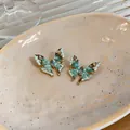 Nahaufnahme der minzgrünen Emaille-Schmetterlingsohrringe mit Perlen und Kristallen - Schmetterling Design / Grün
