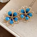 Close-up detail of vintage blue enamel flower jewelry set on a textured beige book cover. - Earrings / 925 Silver Needle / Blue