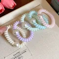 Details von farbenfrohen Spiral-Haargummis mit eleganten Perlen auf einem Tablett. - Mehrfarbig Gemischt Mit Künstlicher Perle