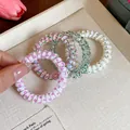 Detailansicht von sommerlichen Spiral-Haargummis im Telefonkabel-Stil in einem Tablett - Rosa Grün Weiß Gemischt Mit Geometrischem Druck