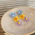 Detailed close-up of colorful daisy drop earrings in light blue, yellow, and purple. - Blue-Yellow-Purple