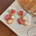 Close-up of vintage geometric resin earrings with red and pink inlays on linen background - Gold-Pink-White