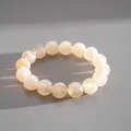 Macro view of creamy marbled acrylic beaded bracelet on a textured grey background - White