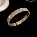 Primer plano de un brazalete abierto con cuatro filas de brillantes y diseño elegante - Estilo de Cuatro Capas / Plateado