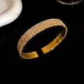 Detalle de una pulsera abierta dorada con cuatro filas de brillantes diamantes - Estilo de Cuatro Capas / Dorado