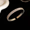Primer plano de un brazalete abierto brillante con varias filas de pedrería plateada elegante - Estilo de Tres Capas / Plateado