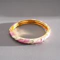 Dettaglio di un bracciale dorato vintage con motivi in smalto rosa e bianco a goccia - Oro-Bianco-Rosa