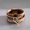Vista macro dettagliata di bracciale in pelle multistrato con ciondolo a cuore dorato - Marrone