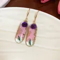 Vista dettagliata di eleganti orecchini in resina con veri fiori secchi rosa e viola - Oro-Rosa-Viola