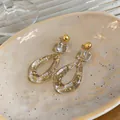 Macro detail of resin drop earrings with elegant gold foil flakes and minimalist design - Irregular Hollow Teardrop Style (HE32258) / Gold & White