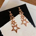 Detail showing hollow rose gold star dangling earrings on textured background - Hollow Star Tassel (HE32033) / Gold