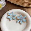 Close-up of light blue enamel flower earrings with zircon center on a white plate. - Flower Shape (HE32525) / Blue