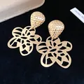 Nahaufnahme eleganter goldfarbener Hohlblumen-Ohrringe mit einem Oberteil in Wabenstruktur - Gold