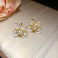 Close-up of elegant flower stud earrings featuring central white pearl and sparkling zircons - Four-Petal Flower Studs / Gold-White