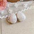 Vista dettagliata di eleganti orecchini a lobo in acrilico marmorizzato bianco a goccia - Stile Perno in Argento / Argento-Bianco