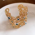 Vista dettagliata di un bracciale a fascia vintage dorato con perline malocchio blu. - Bangle / Oro