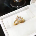 Close-up detail of an elegant gold marquise zircon ring set in a white plush jewelry box - Gold