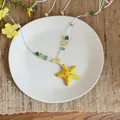 Detailed top view of a yellow ceramic starfish pendant necklace on a white plate - Yellow