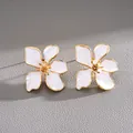Detalle macro exquisito de pendientes de flor en esmalte blanco con bordes dorados - 滴油几何花朵款式 / Blanco