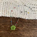 Detailed view of silver chain necklace with colorful beads and green flower pendant - Necklace / Green