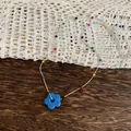 Macro view of a colorful dopamine style beaded necklace featuring a vibrant blue flower - Necklace / Blue