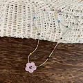 Detailed macro shot of a dopamine style necklace with pink flower and colorful beads - Necklace / Pink