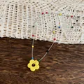 Detailed macro shot of a vibrant yellow flower pendant on a colorful beaded chain. - Necklace / Yellow