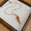 Detailed view of a colorful enamel fish pendant on a gold stainless steel chain. - Fish Pendant (Gold Chain) / Red