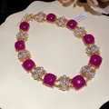 Detailansicht einer Vintage-Goldkette mit magentafarbenen Steinen, Perlen und Strass - Halskette / Lila