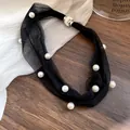 Detail of sweet black mesh necklace featuring white pearls and a crystal magnetic clasp. - Black
