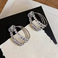 Macro view of elegant silver-toned double-layer circular earrings with sparkling zircon inlays - Clip-On Earrings / 1 Pair Pack / Silver