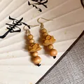 Detailed macro shot of vintage wooden lotus flower drop earrings with Chinese style beads - Brown