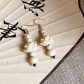 Detailed close-up of Chinese style wooden bead earrings with delicate carved lotus - White
