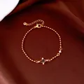 Close-up of elegant gold bead chain bracelet with star zircon detail on brown satin. - Purple Cross Style / Gold