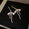 Elegant silver bow earrings featuring white enamel inlay and shimmering zircon detail - Bow Ear Hook Style / Silver