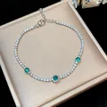Close-up of elegant silver-toned bracelet with sparkling green and clear zircons. - Silver
