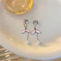 Dettaglio di eleganti orecchini a coda di pesce rosa con perle e zirconi brillanti - Argento-Rosa