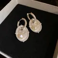 Detailaufnahme eleganter silberner Ohrringe mit ovalen Anhängern und Süßwasserperlen - Ohrbuckle / Silber