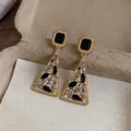 Macro dettaglio elegante di orecchini vintage dorati con pietre nere e trasparenti - Oro-Nero