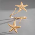 Detail shot of a golden metallic starfish arm cuff with a textured finish on grey background - Gold