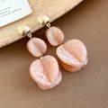 Close-up of elegant peach acrylic drop earrings with gold studs on a textured background - Earrings (Silver Earring Post) / Pink
