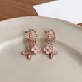 Close-up of elegant rose gold flower earrings with sparkling zircons on a beige plate. - Rose Gold