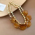 Close-up of double-layered necklace with amber acrylic marbled beads and gold beads - Necklace / Brown