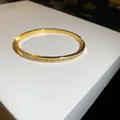 Detailed view of an elegant gold-plated bangle inlaid with sparkling cubic zirconia stones - Buckle Bangle / Gold