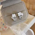 Primo piano di orecchini a lobo a fiore bianco con pendenti in zircone trasparente - Stile Argento / Perno in argento 925 / Bianco