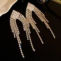 Close-up shot of exquisite silver needle rhinestone tassel earrings on black background - Rhombus Tassel (HE32972) / Gold