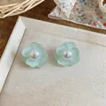 Close-up detail of light green flower stud earrings with elegant pearl center on a tray - Mint Green